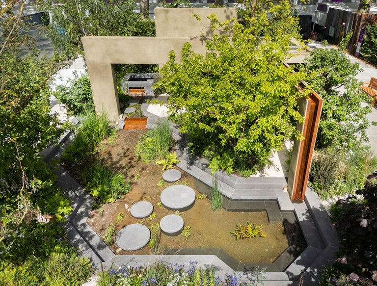 A garden with a tree and a stone arch
