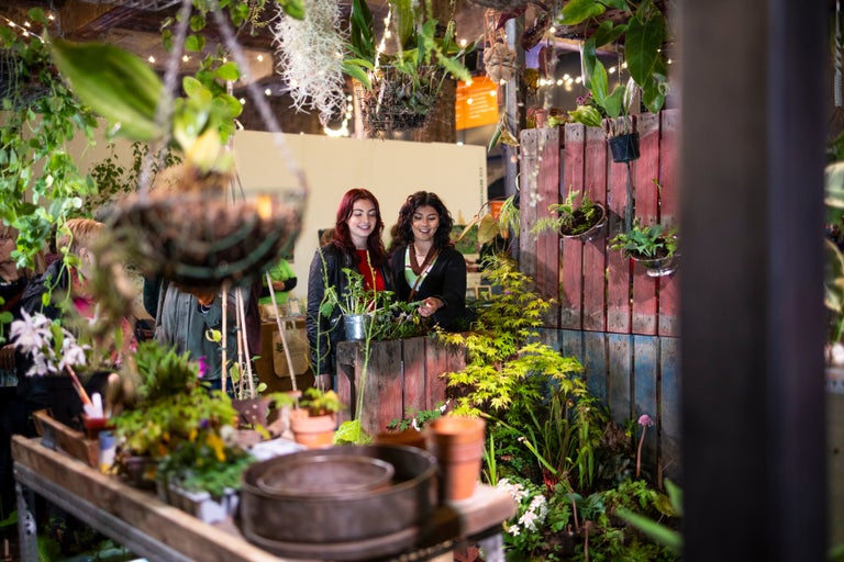 Two women standing next to a plant