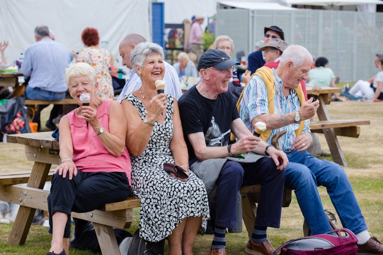 A group of people sitting on benches eating ice cream