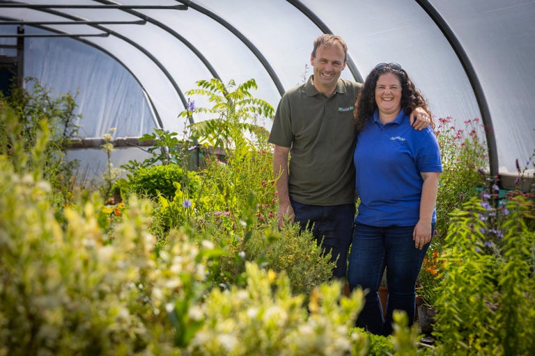 A man and woman standing in a greenhouse