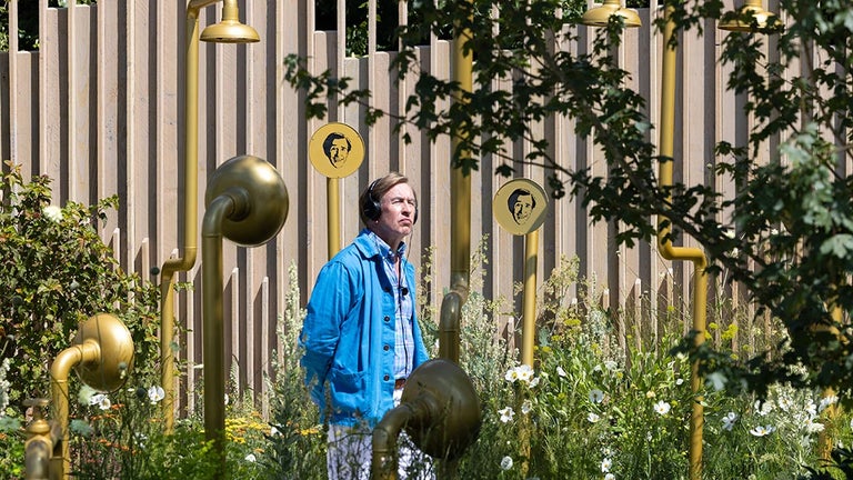 A man wearing headphones standing in a garden