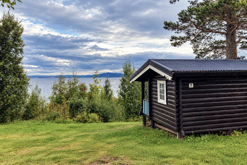 A cabin on the grass by a fjord in Norway