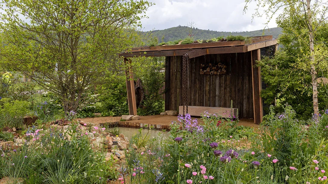 A wooden structure with a pond and flowers