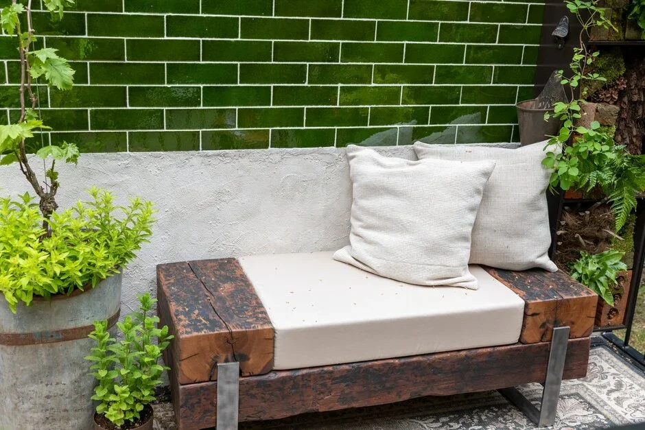 A bench with pillows and plants in front of a wall