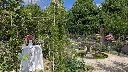 A garden with a fountain and a table