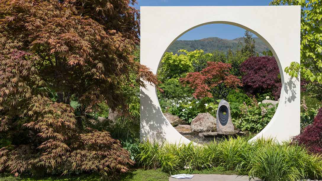 A white wall with a circular arch in the middle of a garden