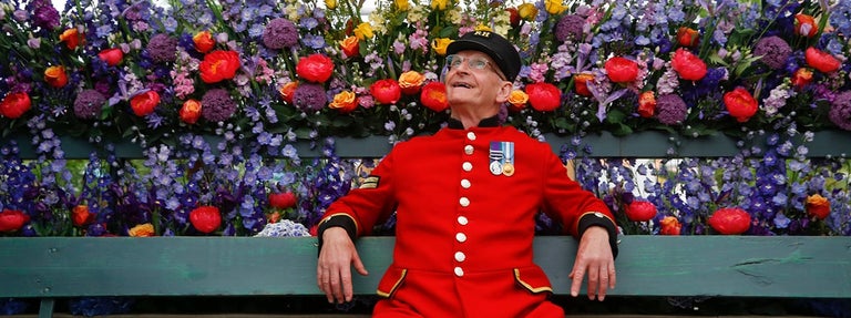 A man in a uniform sitting on a bench with flowers