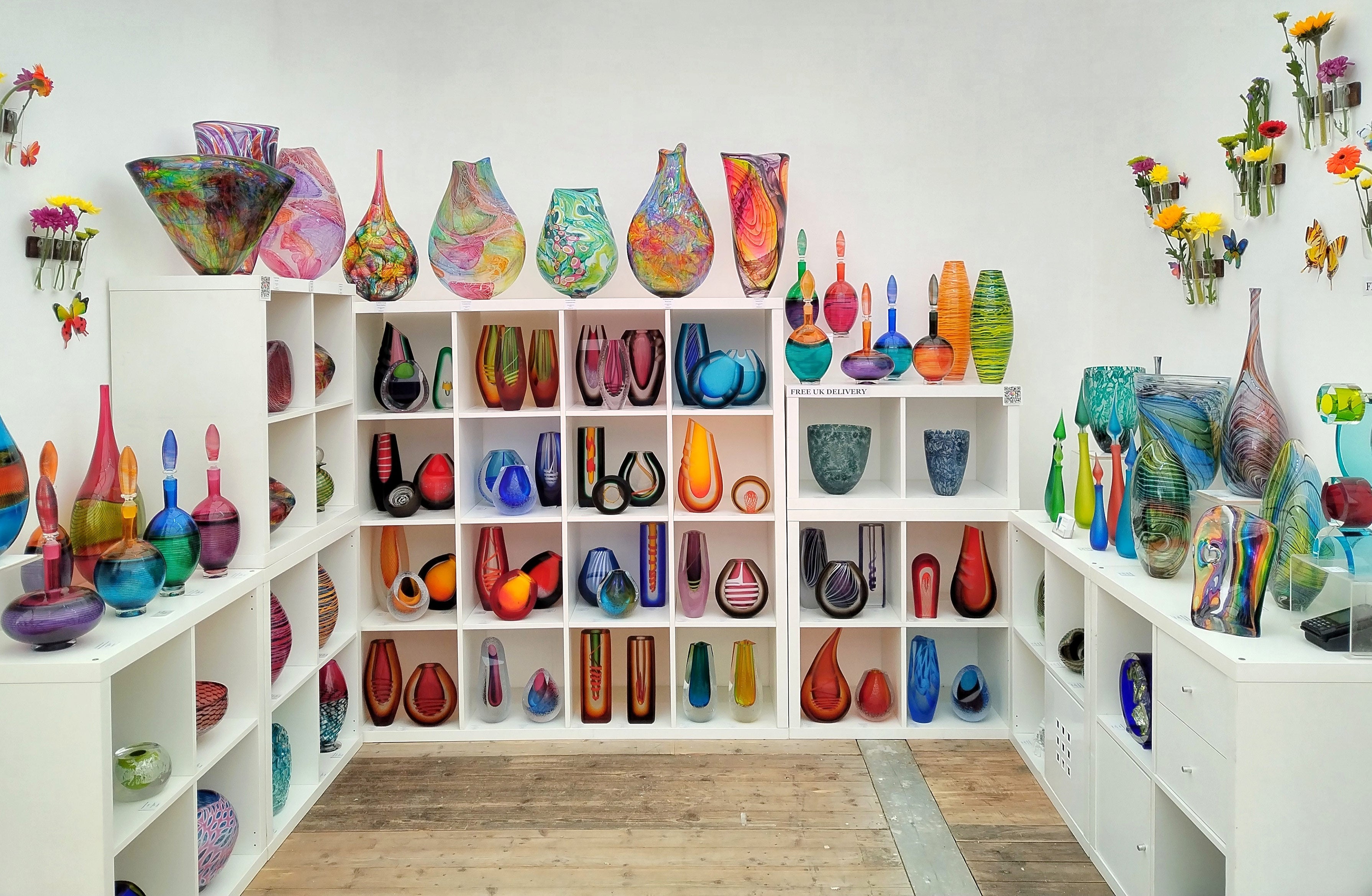A room with shelves full of colorful vases