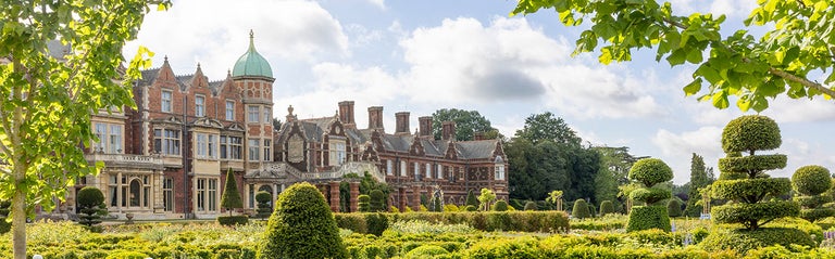A large brick building with a garden in the background