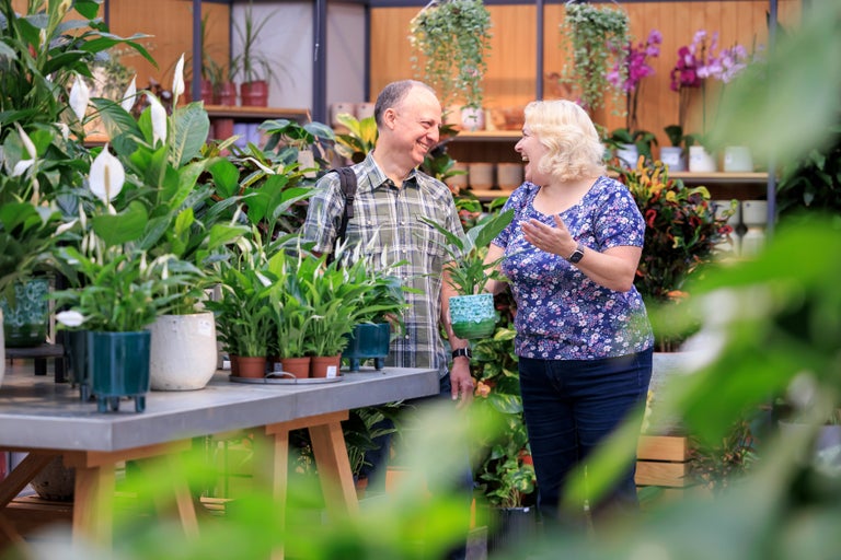A man and woman standing next to a table with plants