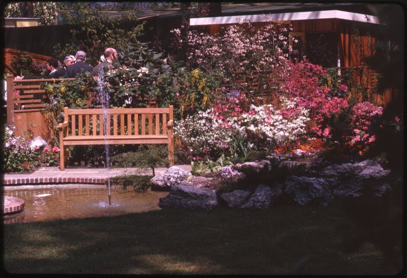 A group of people sitting on a bench near a pond