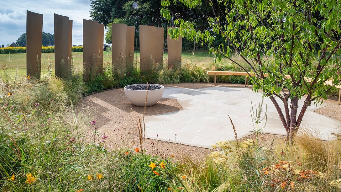 A circular patio with a fire pit and a bench in the middle